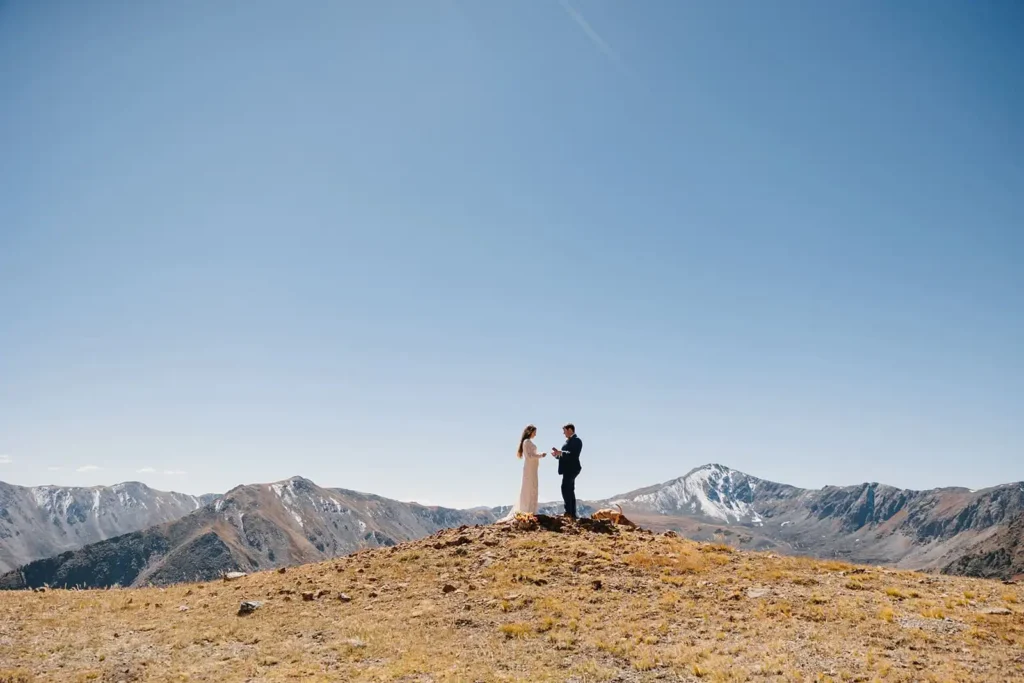 Bride and groom share wedding views on top of a gorgeous mountain peak in the fall in Colorado