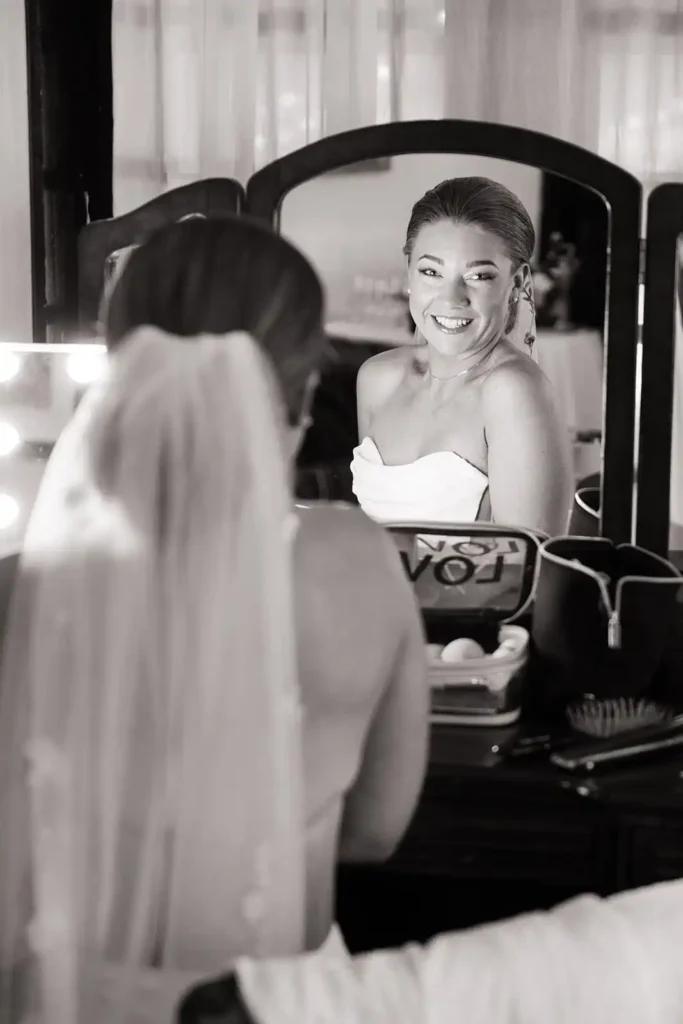 elegant black and white candid photo of bride looking in the mirror while getting ready. Inspiration for must-have wedding photos