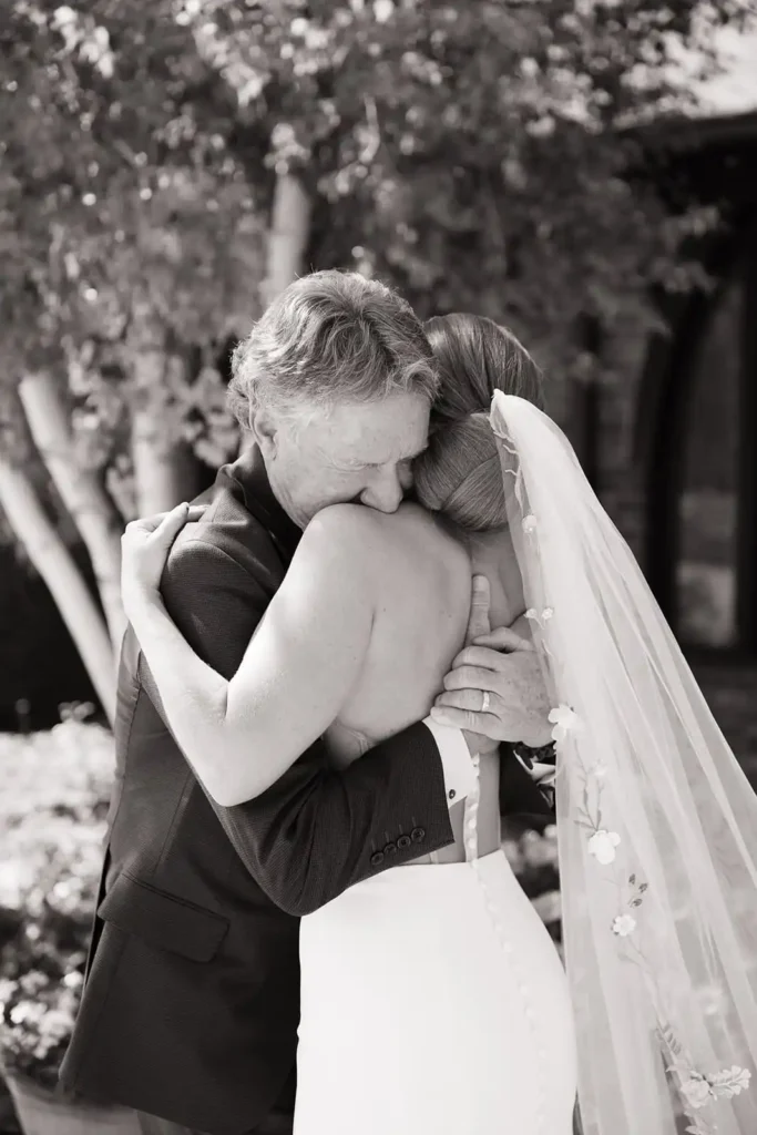 Bride shares a candid moment while sharing a first look with her dad at Wellshire Event Center