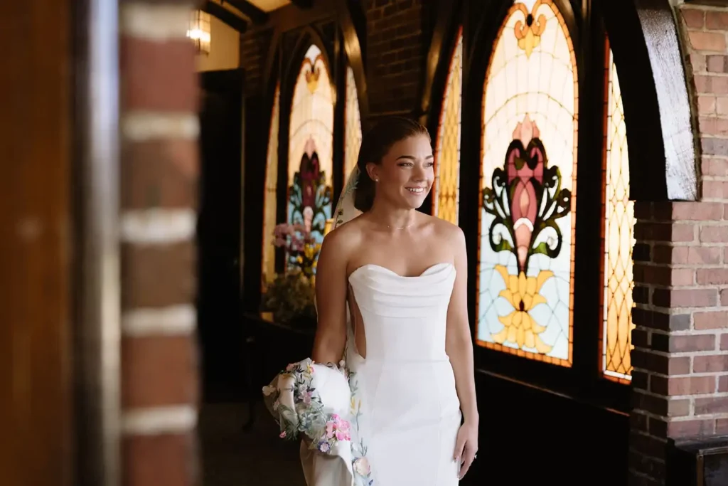 Photo of bride before her first look walking down the hallway holding her wedding dress. Raw, candid, emotional photography, the kind that you don't need on a wedding photography shot list because it happens naturally.