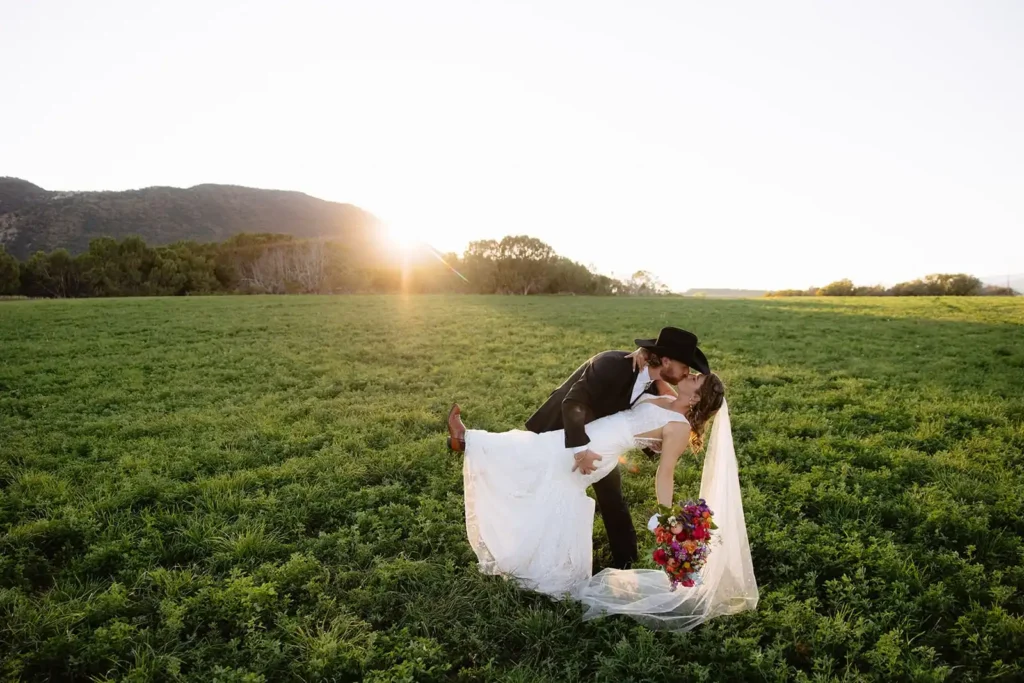 Soft golden light surrounding couple during sunset wedding portraits near lake and mountains.