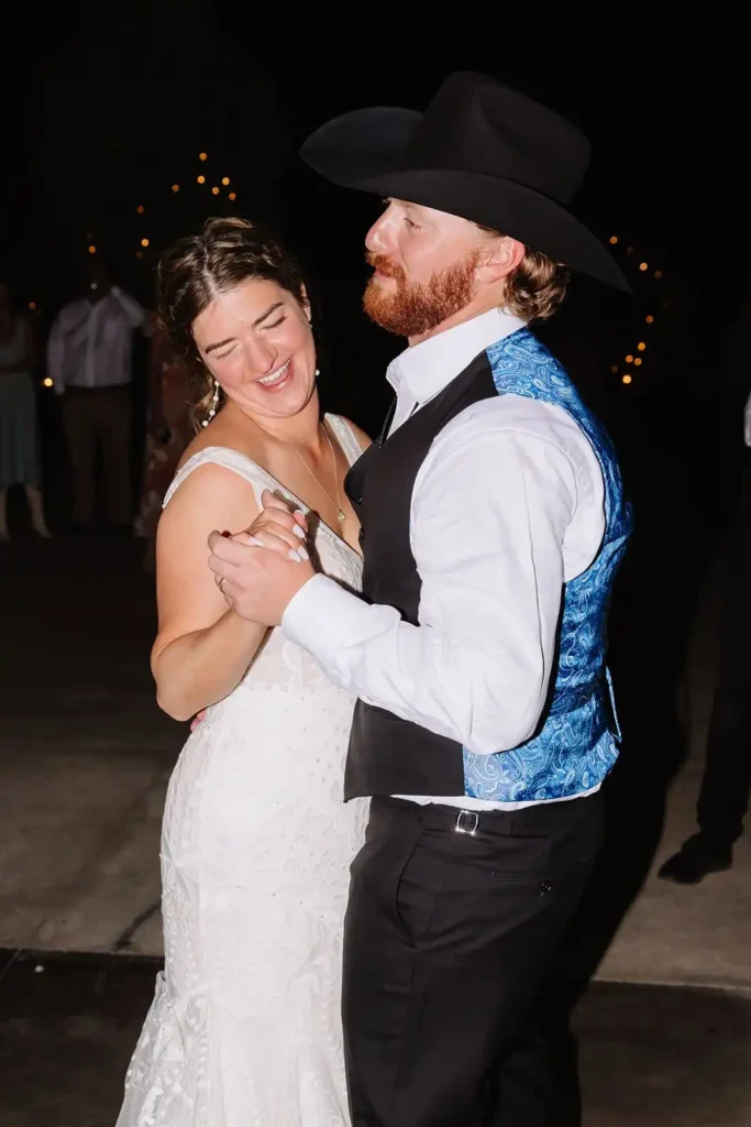Couple surrounded by friends as they dance under mountain night sky.