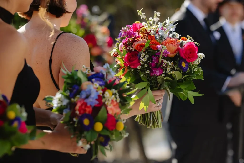 Detail photo of bright wildflower bouquet held by the maid of honor. Summer wedding floral inspiration