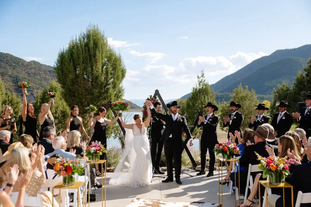 Guests enjoying scenic views of lake and mountains during open-air wedding ceremony.