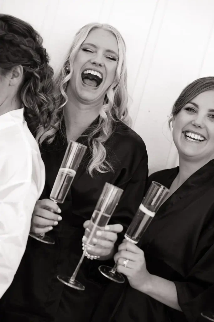 Bride and bridesmaids in black silk robes popping champagne outside the bridal suite at Vista View Events wedding venue near Aspen, Colorado