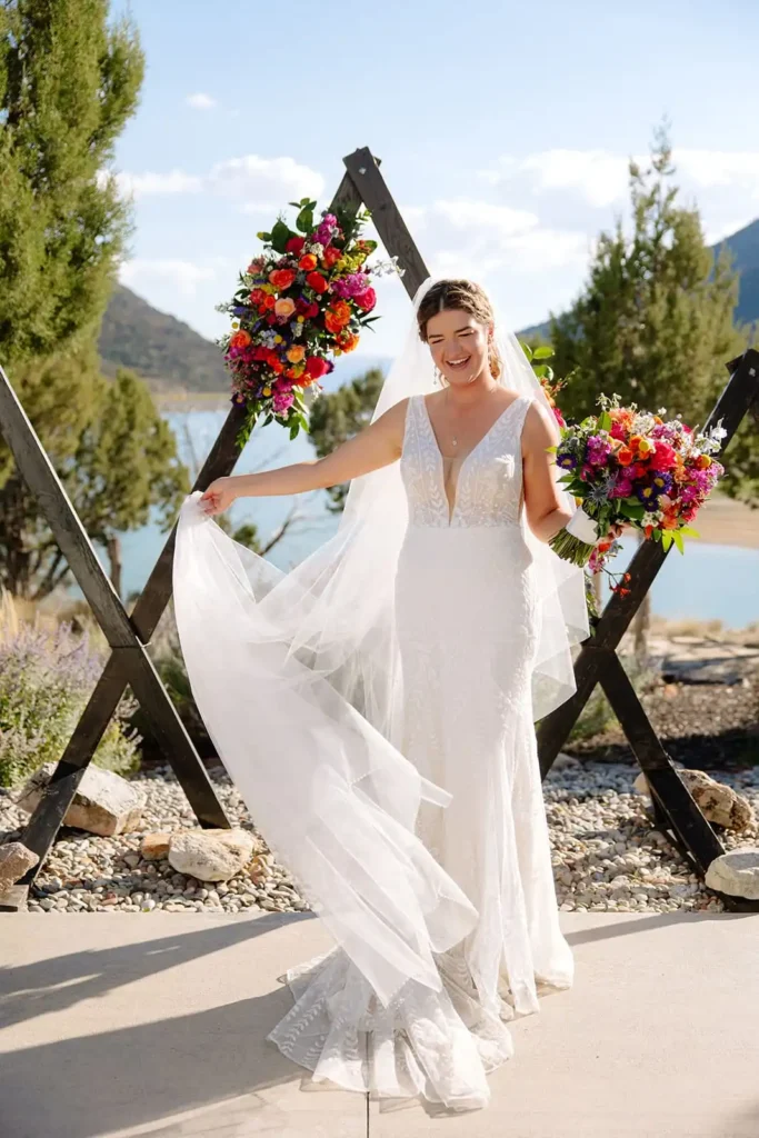 Candid bridal portraits of bride with her dress on a warm summer day. Vibrant floral bouquet with views of the lake and mountains in the background at Vista View Events