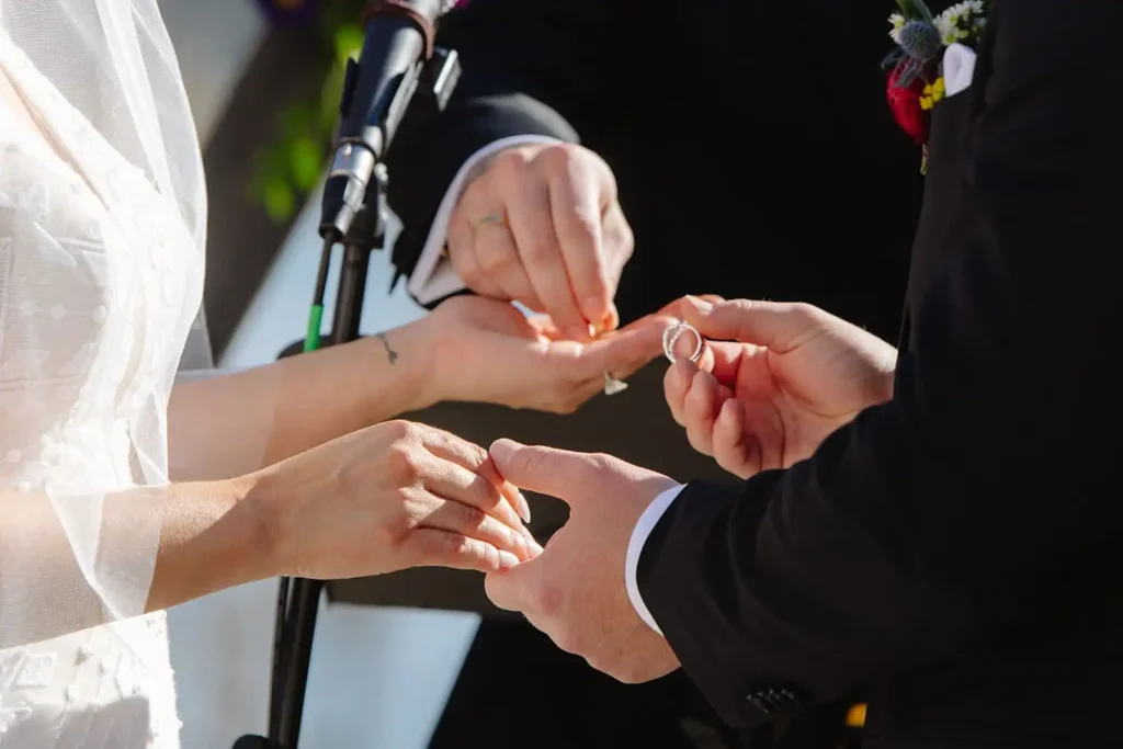 Detail shot of wedding couple exchanging rings during lakeside ceremony at Vista View Events