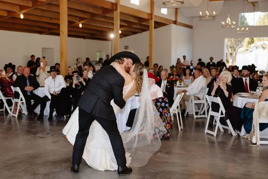 Bride being lifted on the dance floor surrounded by cheering guests at open-air barn reception.