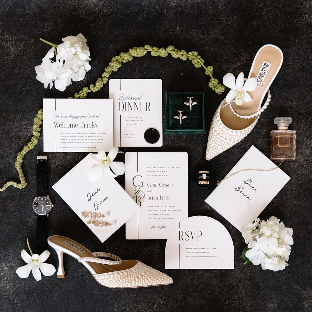 An elegant wedding flat lay photo with dark background, green moss, and luxury details. 