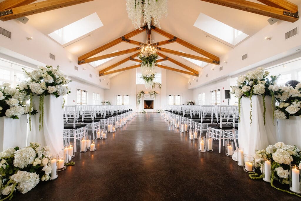 Indoor winter wedding ceremony at The Manor House in Littleton, Colorado, with grand fireplace as backdrop, candles, and hanging floral ceiling installation.